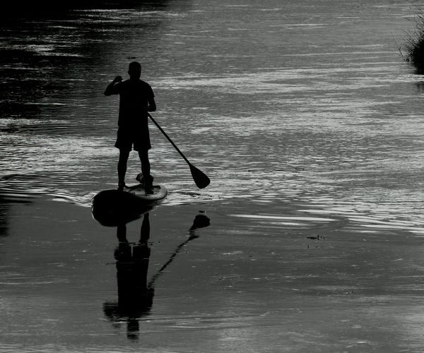 Person stretching outdoors during sunrise, silhouette with cyan highlights.